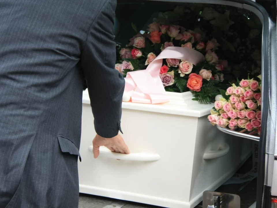 Wyjmowanie trumny z karawany pogrzebowej